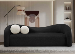 black modern sofa in lounge with neutral rug and paint. Two round pillows on the left.
